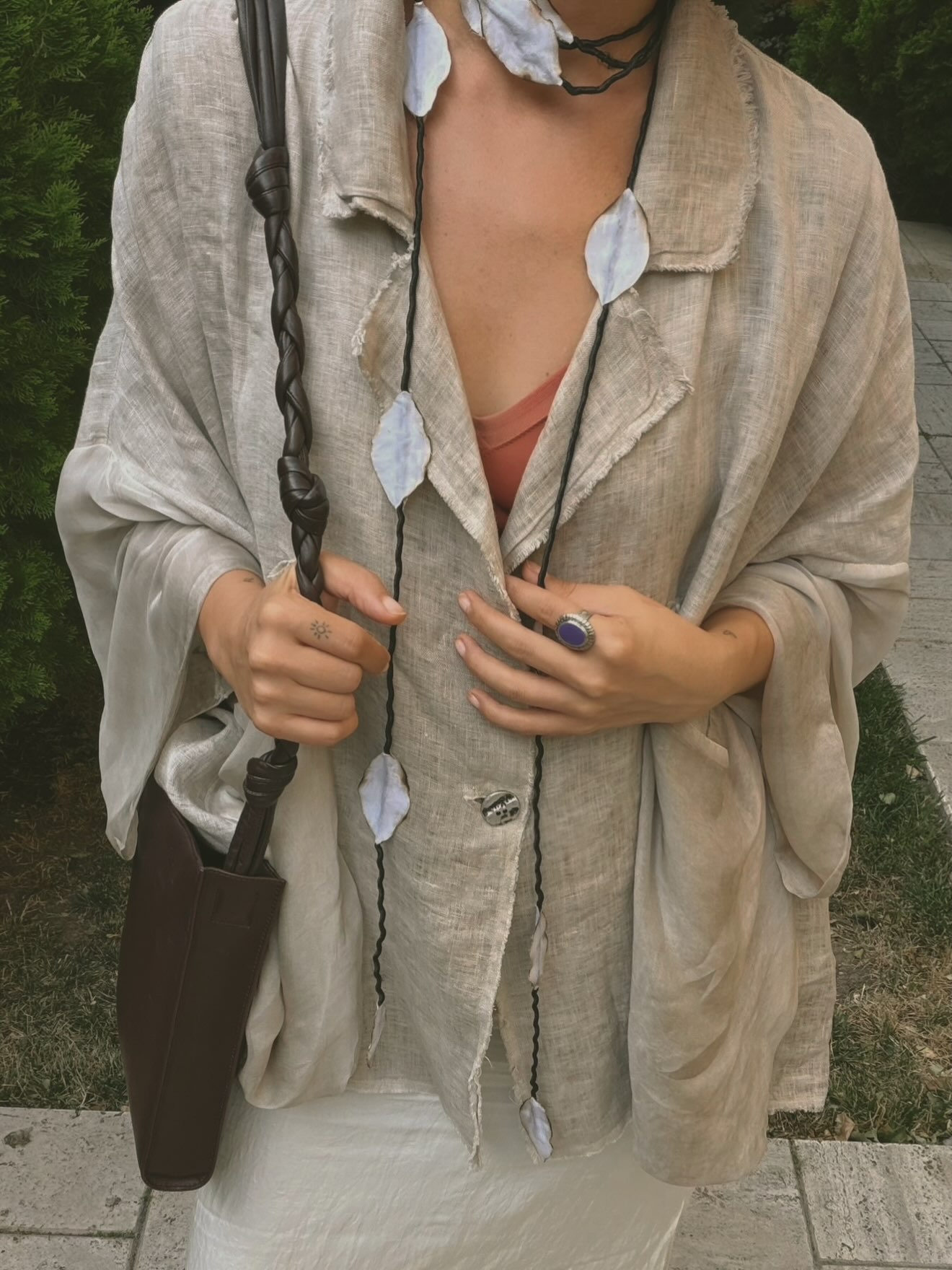 Styling detail: raw-edge linen layers with a long shell necklace and silver ring