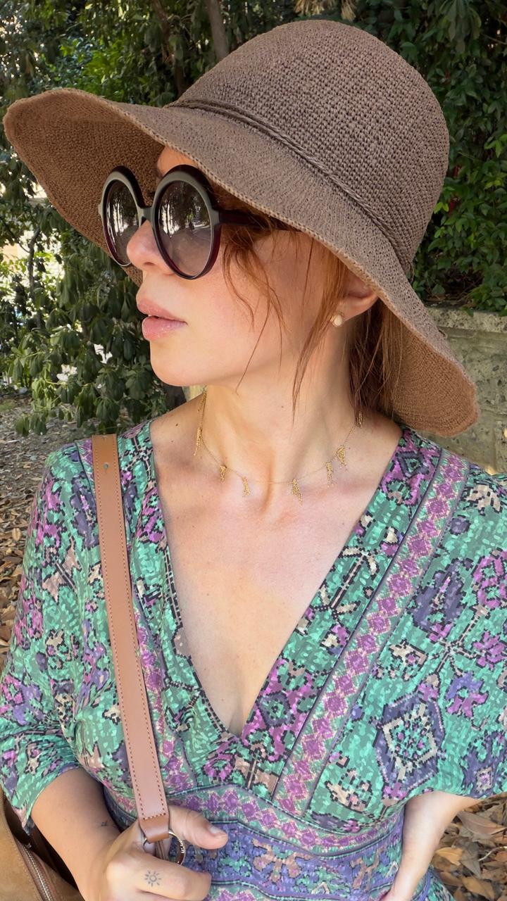 Portrait in a woven straw hat, round sunglasses and a fine gold necklace